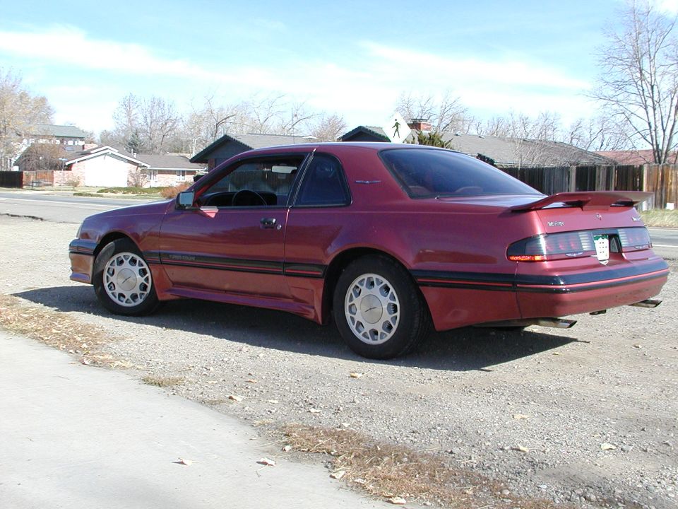 Maroon Ford Thunderbird coupe parked on a dirt lot, rear three-quarter view
