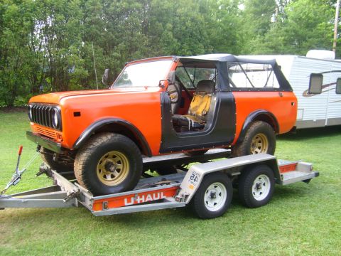 1994 Ford Bronco - An orange International Harvester Scout II is loaded onto a U-Haul trailer, ready for transport.