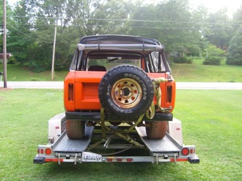 1994 Ford Bronco - An orange SUV with a spare tire mounted on the rear is seen on a trailer.