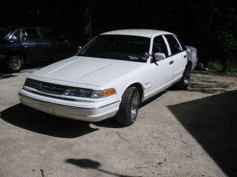 1997 Ford Crown Victoria - A white Ford Crown Victoria is parked outdoors, with another vehicle in the background.