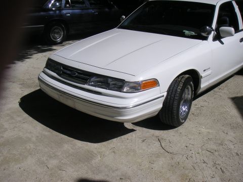 1997 Ford Crown Victoria - The front of a white Ford Crown Victoria is shown, with another dark sedan parked behind it.