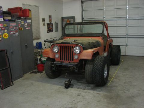 1978 Ford Bronco - This orange Jeep CJ5 is parked in a garage with its hood up and large tires.