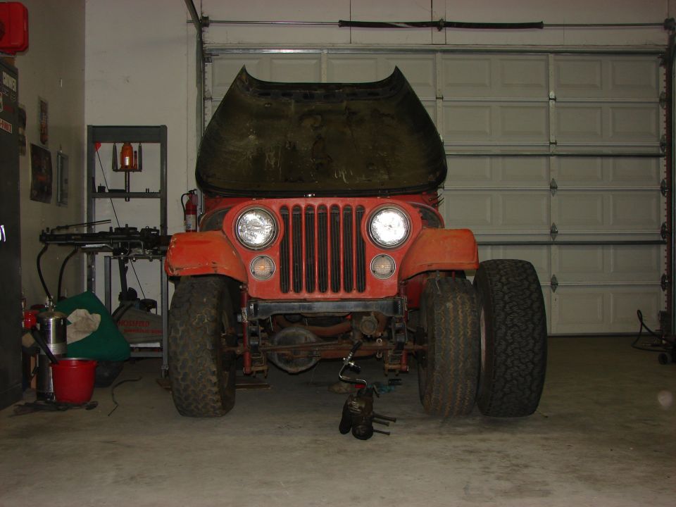 Orange Jeep CJ5 with hood open, parked in a garage
