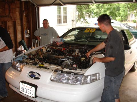 1993 Ford Taurus - Mechanics work on the engine of a 1993 Ford Taurus in a garage.