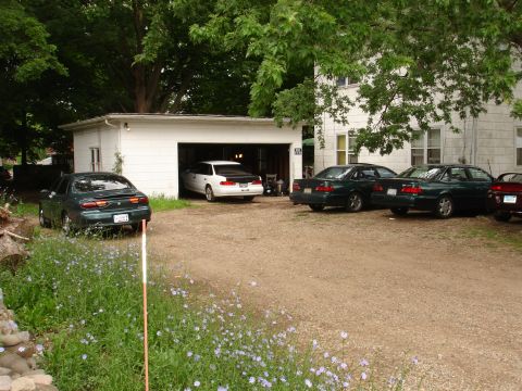 1993 Ford Taurus - A collection of sedans are parked in a driveway, with one white sedan partially inside a garage.