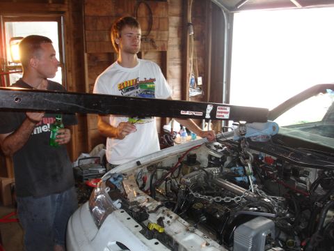 1993 Ford Taurus - Two men work on the engine of a white 1993 Ford Taurus in a garage.