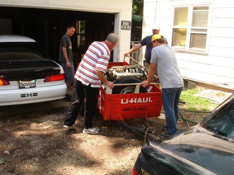 1993 Ford Taurus - A group of men are seen loading a V8 engine into a U-Haul trailer, with a white car parked nearby.