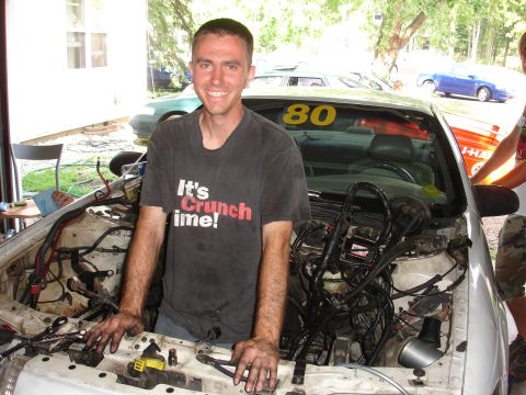 1993 Ford Taurus - A man stands with his hands in the engine bay of a car, with a racing number '80' visible on the windshield.
