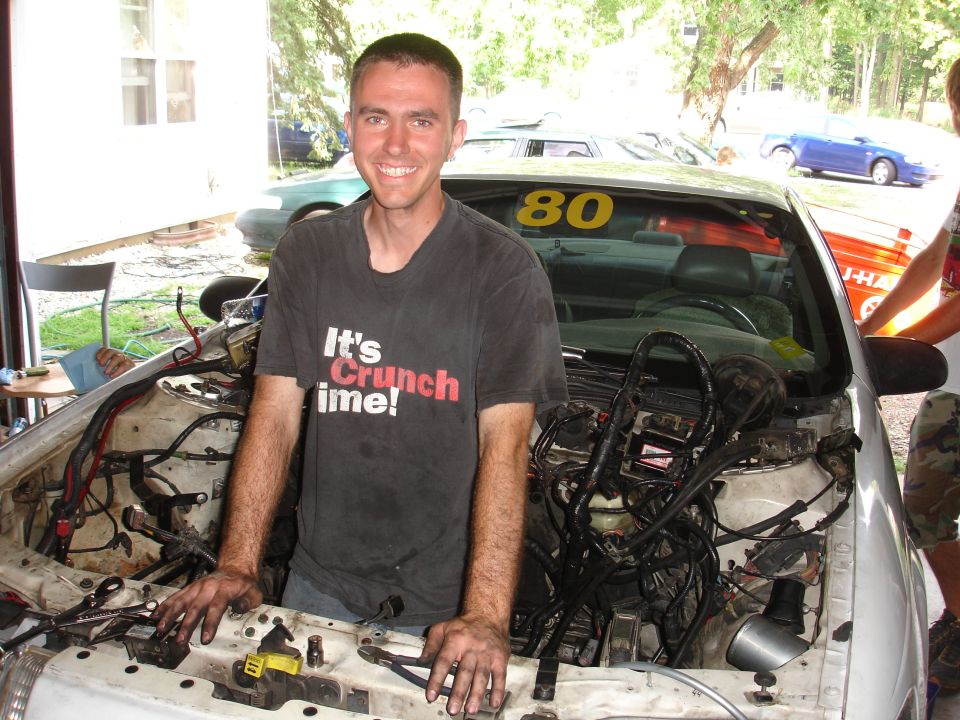 guy with 'It's Crunch time!' shirt in front of car engine bay, number 80 on windshield