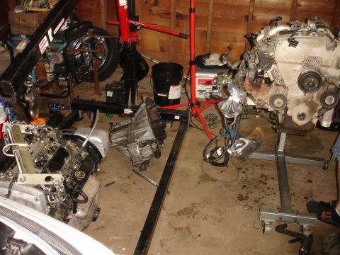 1993 Ford Taurus - Engine and transmission parts are disassembled and staged in a garage, likely for repair or rebuilding.