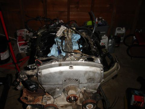 1993 Ford Taurus - An engine assembly sits on a stand in a garage, surrounded by various fluids and tools.