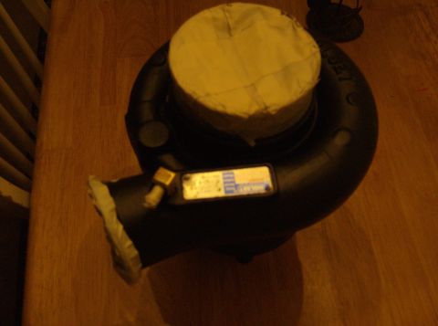 1996 Ford Probe - A turbocharger sits on a wooden surface, showing a data plate with some text and numbers.