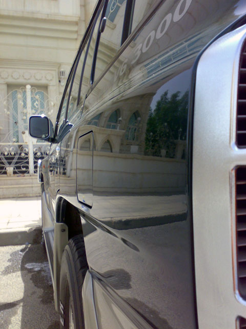 2000 Mitsubishi Montero - A black SUV is parked in front of a building with ornate architecture. The side of the vehicle reflects the surroundings.