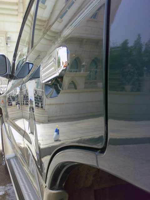 2000 Mitsubishi Montero - Side view of a dark SUV with chrome accents, reflecting a building and trees.