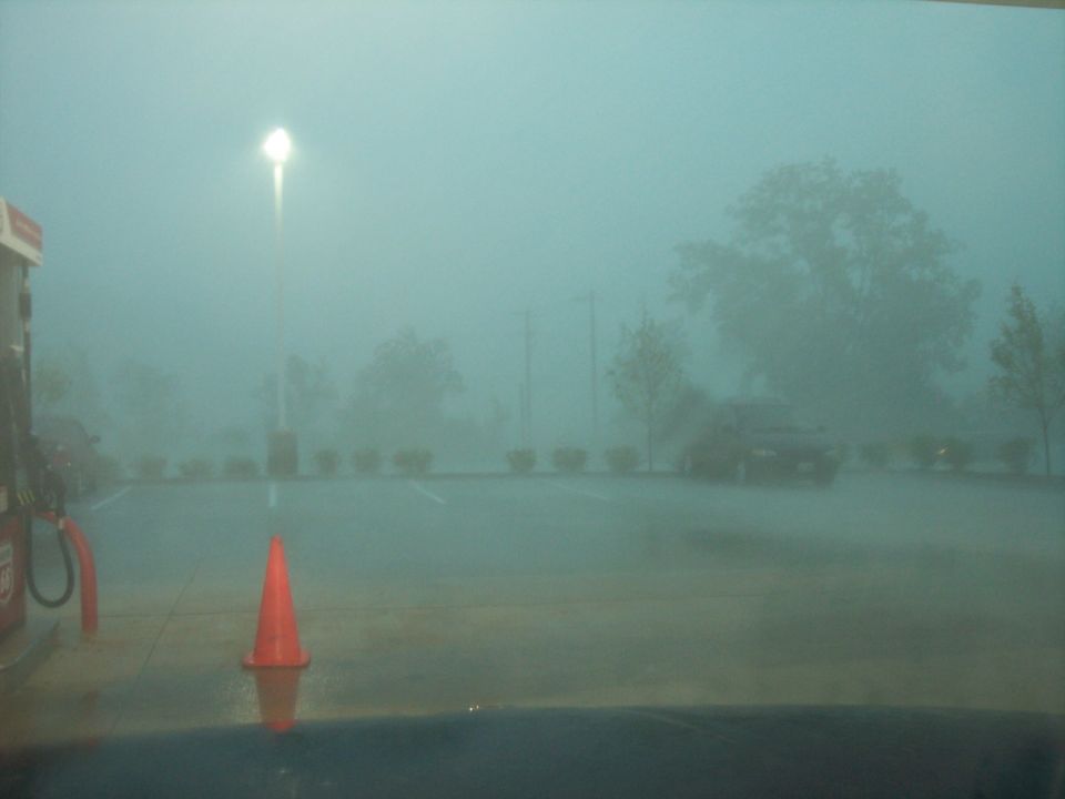 foggy parking lot with a gas pump and a traffic cone