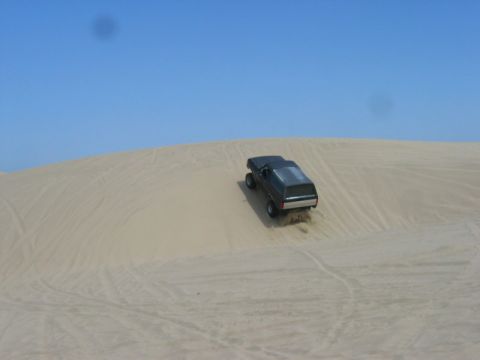 1989 Ford Bronco - Ford Bronco navigates a sandy incline on a clear day.