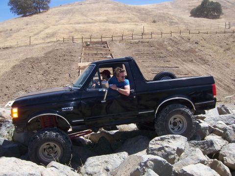 1989 Ford Bronco - 1989 Ford Bronco navigating a rocky trail with a driver and passenger.
