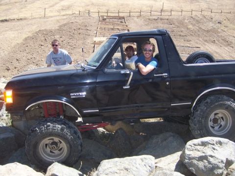 1989 Ford Bronco - A black Ford Bronco navigates a rocky trail with three occupants enjoying the off-road adventure.