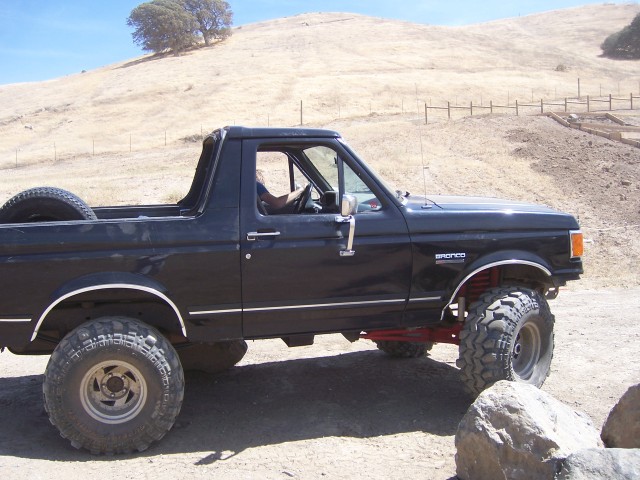 Black Ford Bronco with lifted suspension and large tires parked on a dirt road