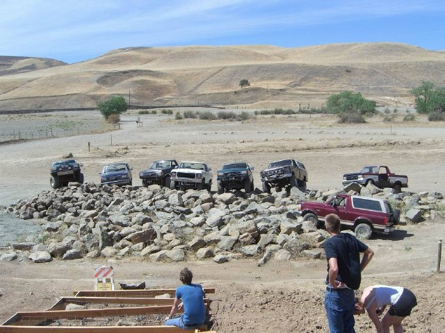 Red 1989 Ford Bronco parked on rocks with other SUVs and trucks