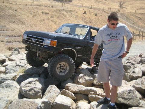 1989 Ford Bronco - A man stands near a black Ford Bronco navigating a rocky terrain.