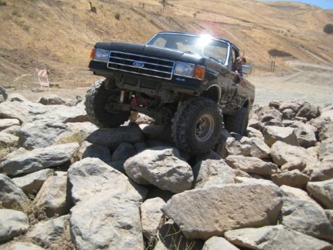 1989 Ford Bronco - A black 1987 Ford Bronco navigates a rocky trail, demonstrating its off-road capabilities.