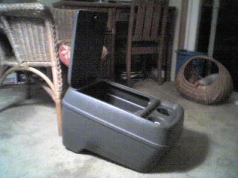 1989 Ford Bronco - A gray plastic center console with an open lid and cup holders sits on the floor.