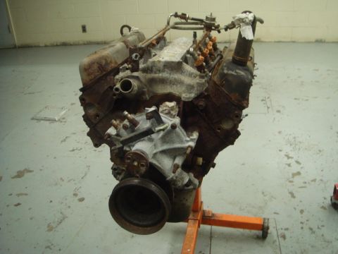 1996 Ford Bronco - V8 engine on an orange engine stand, showing fuel injectors and pulley. The engine appears to be in used condition.