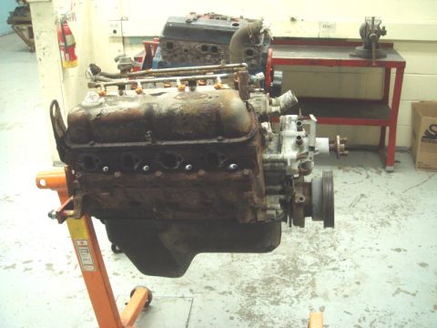1996 Ford Bronco - A V8 engine, appearing to be in a state of disrepair, is mounted on an engine stand in a workshop setting.