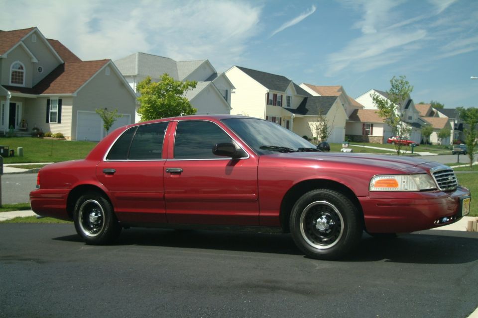 Red Ford Crown Victoria sedan parked in a suburban driveway