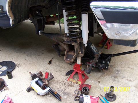1979 Ford F-150 - Tools and disassembled suspension components are laid out on the ground next to a vehicle undergoing repair.