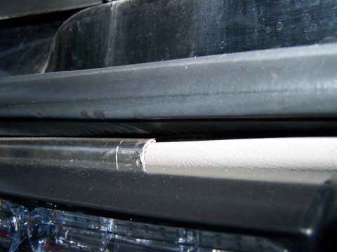 2003 Ford Crown Victoria - A close-up shot focuses on the damaged edge of a vehicle's black trim piece.