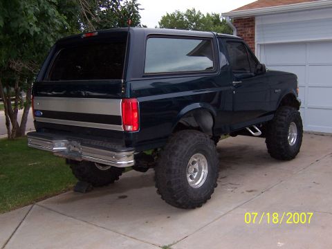 1994 Ford Bronco - This lifted 1994 Ford Bronco features a dark green paint job with a silver stripe accent and a chrome rear bumper.