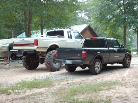 1990 Ford F-150 - A white 1990 Ford F-150 pickup truck with a trailer is parked next to a black Ford Ranger.