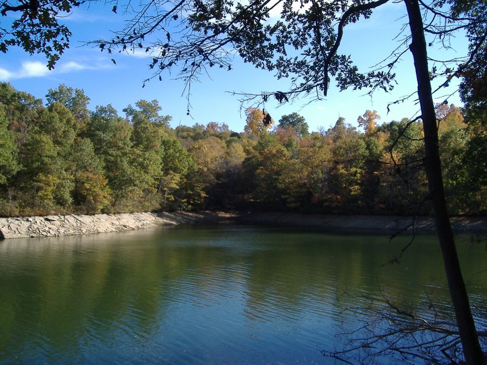 Lake with rocky shore and trees in autumn colors under a blue sky
