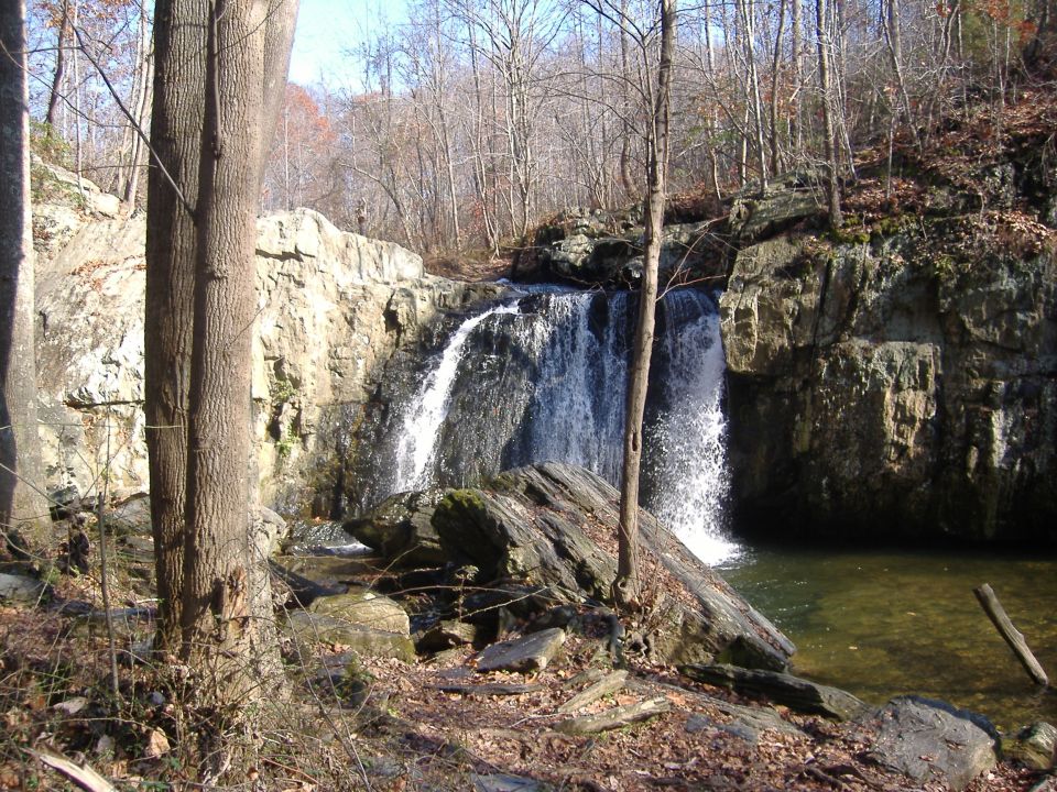 Waterfall cascading over rocks in a wooded area with bare trees