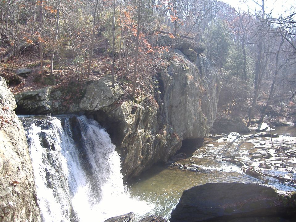 Waterfall in a rocky, wooded area with a SuperMotors watermark