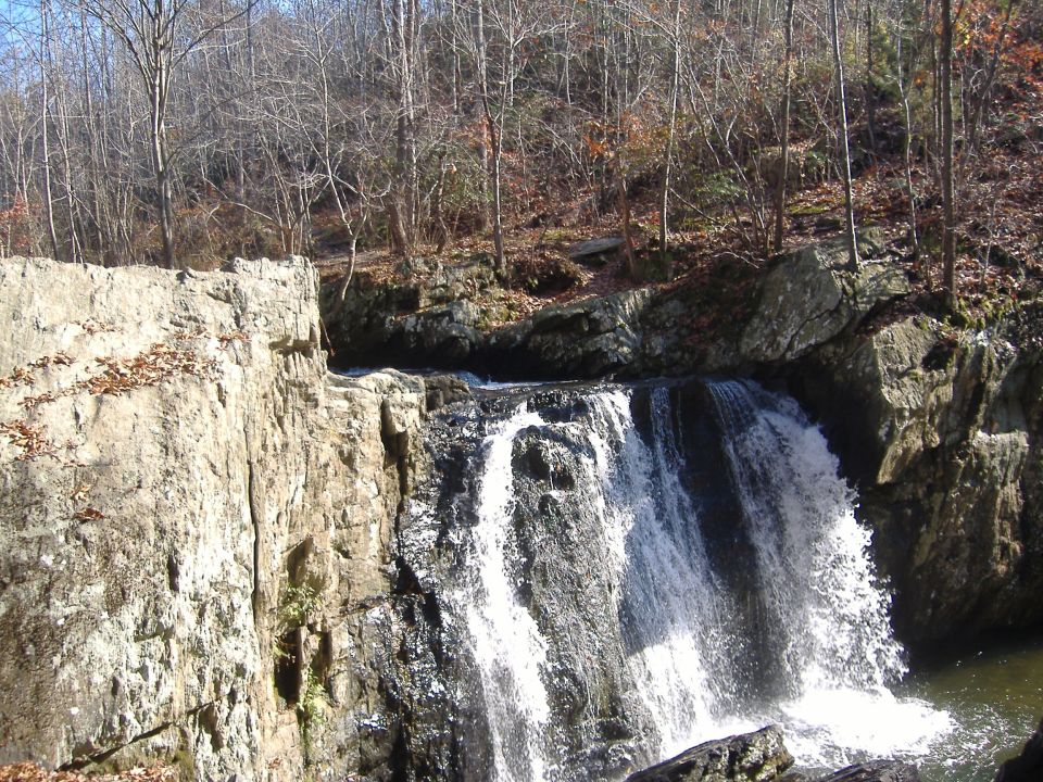 Waterfall cascading down rocks with trees and a cliff face