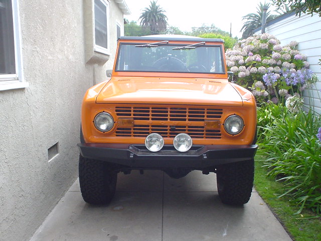 Front view of an orange 1977 Ford Bronco parked in a driveway