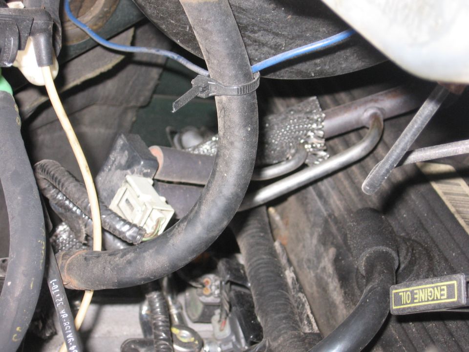Engine bay close-up with zip-tied black hose, white connector and ENGINE OIL dipstick label