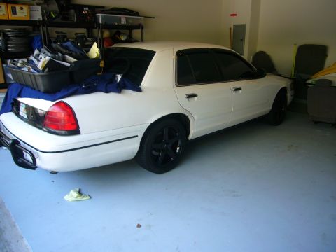 2000 Ford Crown Victoria - Rear view of a white 2000 Ford Crown Victoria with black rims parked in a garage.