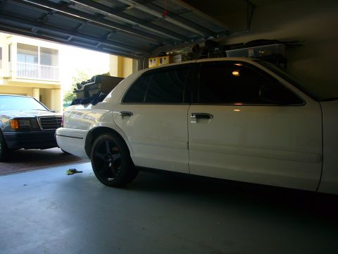 2000 Ford Crown Victoria - A white 2000 Ford Crown Victoria is parked next to another car in a garage.