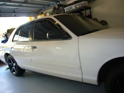 2000 Ford Crown Victoria - A white 2000 Ford Crown Victoria is parked in a garage, its side profile and aftermarket black wheels.