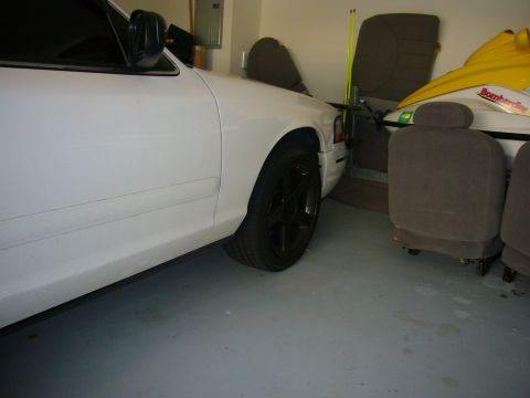 2000 Ford Crown Victoria - Side view of a white 2000 Ford Crown Victoria in a garage, showing the front wheel and fender.