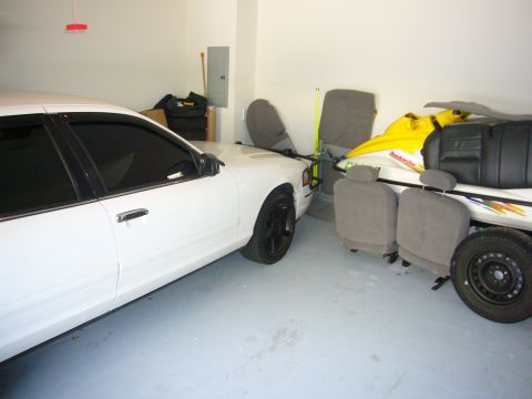 2000 Ford Crown Victoria - A white 2000 Ford Crown Victoria is parked inside a garage, with a jet ski and car seats nearby.