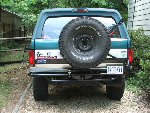 1996 Ford Bronco - Rear view of a 1996 Ford Bronco, a spare tire, aftermarket bumper, and various decals on the tailgate.