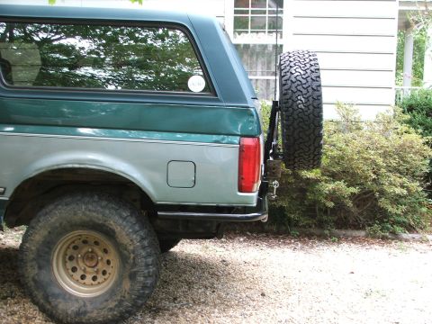 1996 Ford Bronco - Rear view of a two-tone Ford Bronco with a spare tire on the tailgate.