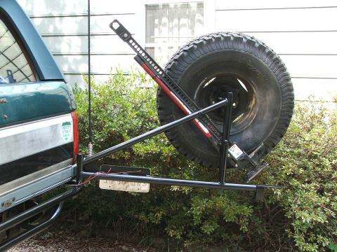 1996 Ford Bronco - Rear view of a green SUV a spare tire carrier and a Hi-Lift jack mounted on the back.