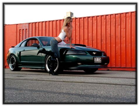 1998 Ford Crown Victoria - Woman poses on a green Ford Mustang in front of an orange industrial container.