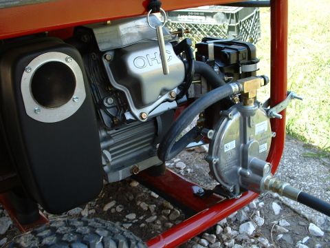 1978 Ford Bronco - Close-up view of a generator's engine components, including the OHC valve cover and propane regulator.